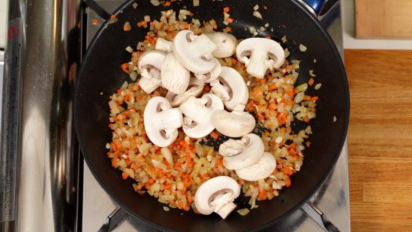 Continue to stir-fry but be sure not to burn them. When the garlic starts to grow more fragrant, season them with salt and pepper. Add the button mushrooms and stir-fry.