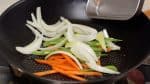 Now, heat the vegetable oil in a pan. Add the sliced carrot, string bean pods and onion.