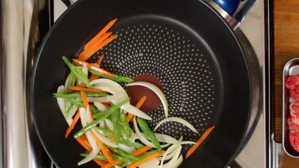 Stir-fry the vegetables and distribute the oil evenly. When slightly softened, gather the vegetables over to one side, making a space for the meat.