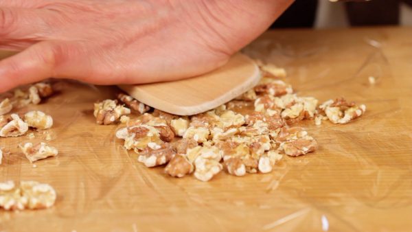 Press the rest of the walnuts with a wooden paddle, breaking them into fine pieces. These are unsalted roasted walnuts but we toasted them again at 120 °C (250 °F) for 5 minutes to bring out the nutty flavor.