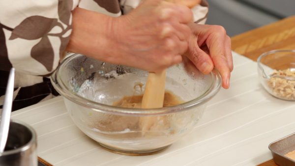 Wet a wooden paddle and quickly mix the mochi.