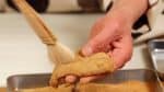 Ora, prendete in mano n pezzo di mochi e spolverate via la farina di soia in eccesso con l'aiuto di un pennello da cucina.