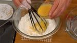 Tuangkan telur kocok lepas kedalam bagian tengah tepung saat kamu sedang mengaduk" adonan.
