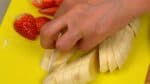 Corte a banana em fatias finas fazendo cortes diagonais. Corte uma das fatias ao meio no sentido do comprimento para a cobertura.