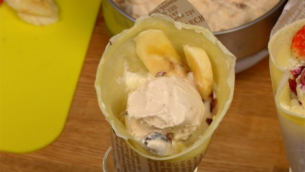 Next, put a scoop of the rum raisin ice cream into the banana crepe. Garnish with the banana slices.