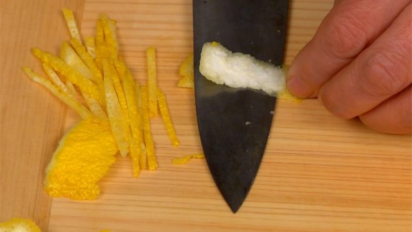 Remove the bitter white pith with the tip of the knife. Press both edges of the peel onto the cutting board with your fingertips as shown so that you can easily remove the pith. Shred the yuzu peel into thin strips.