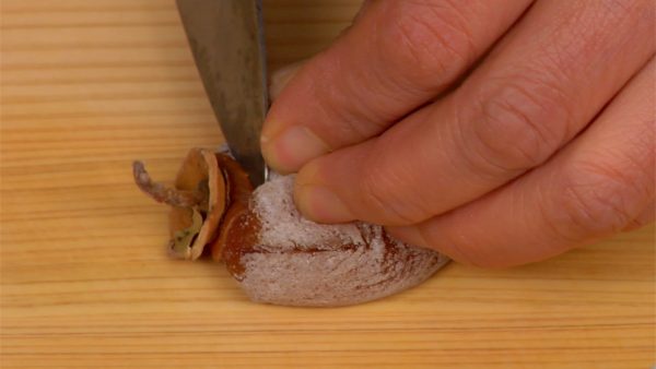 Retirez la tige du kaki persimon séché et coupez-le en deux.