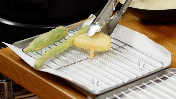 Faites frire jusqu'à ce qu'ils soient bien dorés. Égouttez bien l'excès d'huile et placez le kushikatsu sur une grille. 