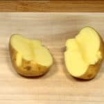 Rinse the surface of the potato thoroughly. Cut the potato in half but leave the skin attached.