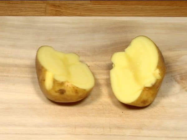 Rinse the surface of the potato thoroughly. Cut the potato in half but leave the skin attached.
