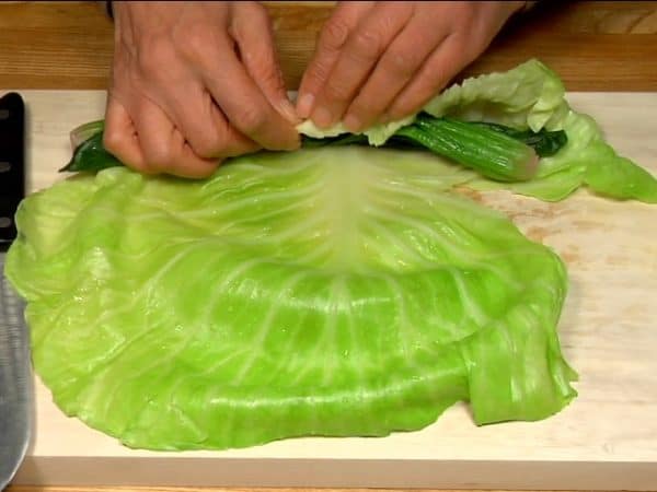 Place the spinach on the cabbage leaf and roll it tightly.