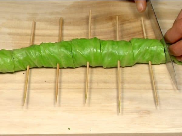 Skewer the cabbage roll with long bamboo sticks in 3 to 4 cm (1.2"~1.6") intervals. Cut the cabbage roll between the bamboo sticks.