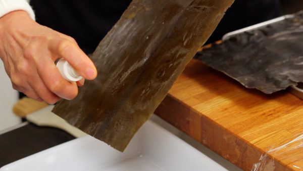 Ensuite, aspergez les deux côtés du kombu avec du saké. Vous pouvez aussi humidifier une serviette en papier avec du saké et essuyer doucement le kombu.