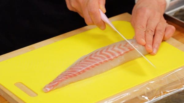 Le kobujime peut être fait avec un bloc de poisson, mais nous utilisons du sashimi en tranches pour préparer le kobujime rapidement. Placez un bloc de tai (dorade rouge) sur une planche à découper avec le côté épais face à vous.