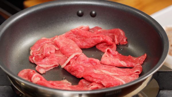 Let's make Nikujaga. Heat about a half tablespoonful of vegetable oil in a pan. Arrange the beef slices on the pan.