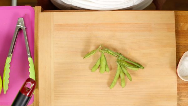 First, remove the stems from the edamame bean pods.