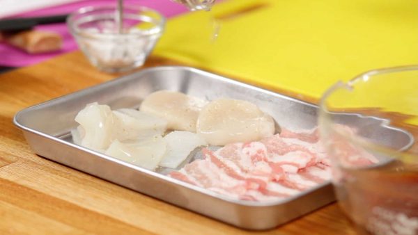 Pour le calamar et la coquille saint jacques en tranches, ajoutez le sel, le poivre et le sake. Malaxez les assaisonnements dans les fruits de mer. 