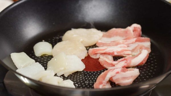 Ensuite, faites cuire le porc et les fruits de mer. Ajoutez une petite quantité d'huile à nouveau. Placez les tranches de porc, le calamar et les saint jacques dans la poêle.