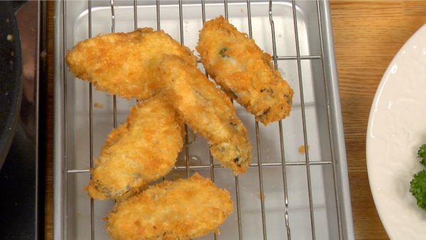 Now, remove the kaki fry with a mesh strainer, drain the excess oil and temporarily place them onto a cooling rack.