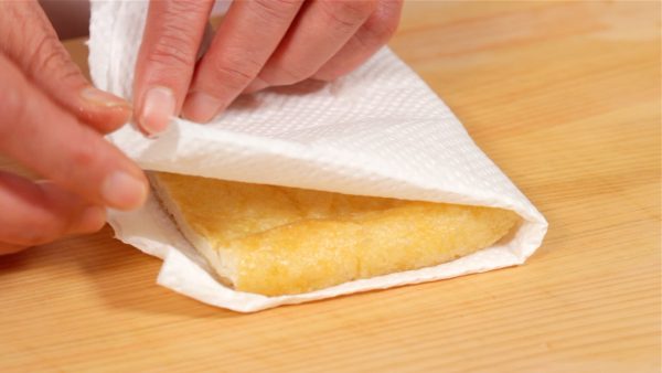 With a paper towel, remove the excess oil and moisture from the aburaage, thin deep-fried tofu.