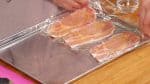 Cover the pork slices with plastic wrap and then flip them over.