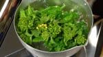 Next, add the salt to the same pot of boiling water. Now, place the stem ends of the nanohana into the water, and then submerge the leaf part. Nanohana is a Japanese spring vegetable which is related to rapeseed or canola plants.