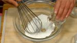 次はぎゅうひ（求肥）を作ります。ボールに白玉粉を入れ、水を徐々に加えながら泡立て器でしっかり混ぜます。