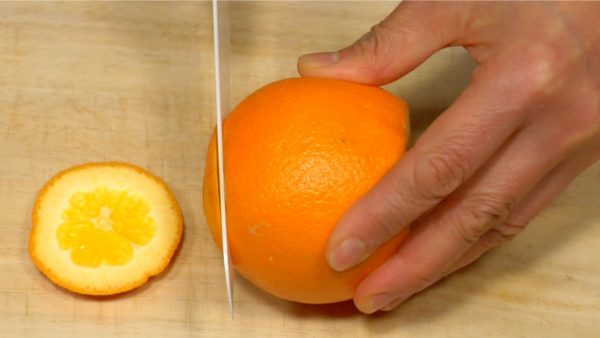 Vamos a cortar la naranja navel ahora. Corta la parte superior e inferior de la naranja.