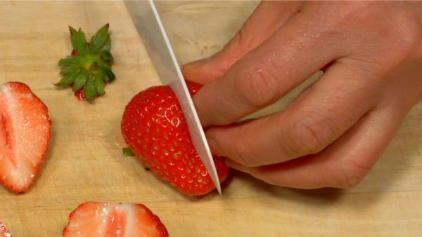 Let's cut the strawberries. Trim off the stem ends. Cut the strawberries vertically in half.