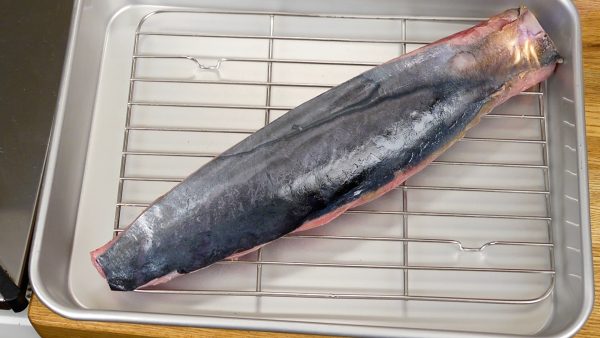 First, let’s sear the katsuo, sashimi-grade skipjack tuna. Place a broiling rack in a tray and put the fillet on it. Sear the skin thoroughly with the kitchen torch. This will help to make it nice and crispy.