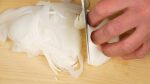 Retirez la partie racine de l'oignon nouveau, aussi appelé oignon jeune. Coupez-le en tranches fines le long des fibres. 