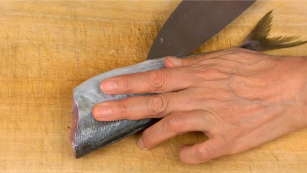 Place the aji diagonally on a cutting board to make it easier to fillet. While tilting the blade, make a shallow angled cut along the belly.