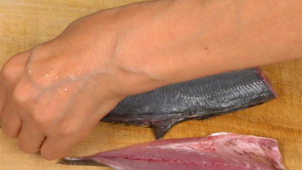 Insert the knife into the tail end, hold the tail fin and slide the blade along the backbone, removing the other fillet.