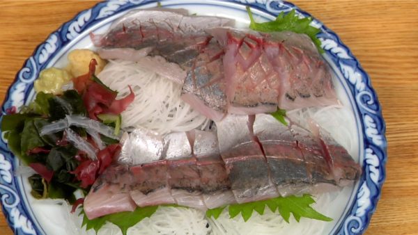 Placez le sashimi sur une assiette garnie avec du daikon en aiguilles, des feuilles de shiso et de la salade d'algues.