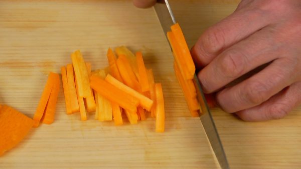Cut the carrot into thin slices and then slice into thin strips.