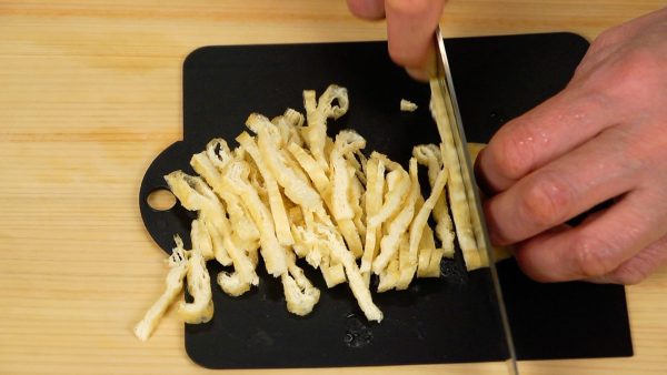 Cut the aburaage, thin deep-fried tofu in half and slice into thin strips. Remove the excess oil with a paper towel before slicing.