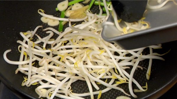 Now, turn on the burner and add the moyashi bean sprouts. Stir-fry the vegetables on high heat and distribute the oil evenly.