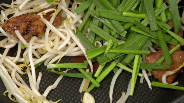 Add the nira garlic chives and continue to stir-fry.