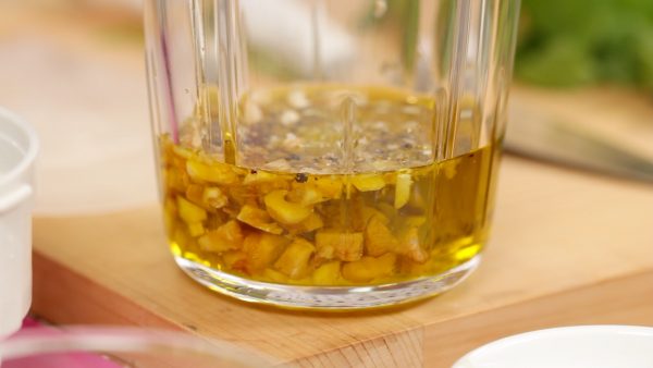 Maintenant, versez l'huile d'olive extra vierge dans le bol du mixeur. Ajoutez la gousse d'ail hachée, les noix torréfiées, du sel et du poivre noir.