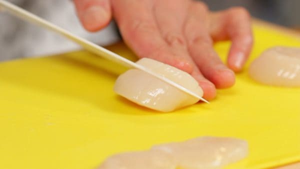 Et maintenant, préparez le carpaccio. Coupez chaque saint-jacques en 3 tranches. Veillez à utiliser des saint-jacques fraîches pour sashimi. Entre chaque découpe, essuyez le couteau avec un torchon mouillé pour aider à faire une découpe nette.