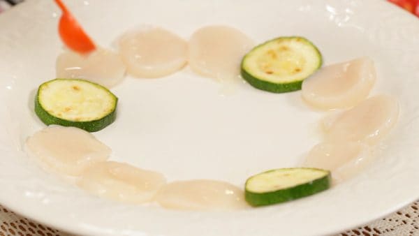 Place zucchini slices onto a plate and arrange the scallops between them. Drizzle on the lemon juice.