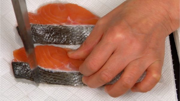 Let's prepare the salmon fillets. Using the back of the knife, scrape off the gooey film on the skin.