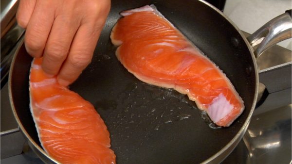 Place the salmon fillets onto the pan with the skin side facing down.