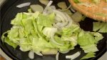 Add the onion slices. Distribute the cabbage leaves onto the griddle.