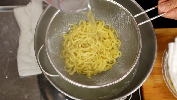 Now, strain the noodles with a mesh strainer. Pour water over them to cool.