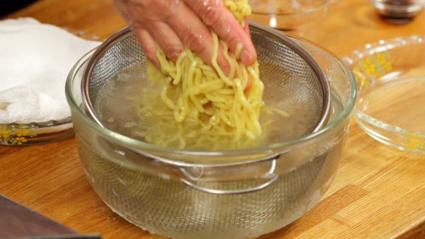 Then, submerge the noodles in a large amount of cold water and rub them to remove the gooey texture on the surface. We are demonstrating every step on the counter, but you should rinse them thoroughly with running water.