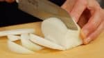 Siguiente, retira el corazón de las cebollas cortadas a la mitad, corta en rodajas de 1 cm (0.4'') de grosor.
