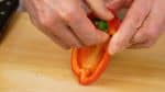 Remove the stem end and the seeds of the red bell pepper.