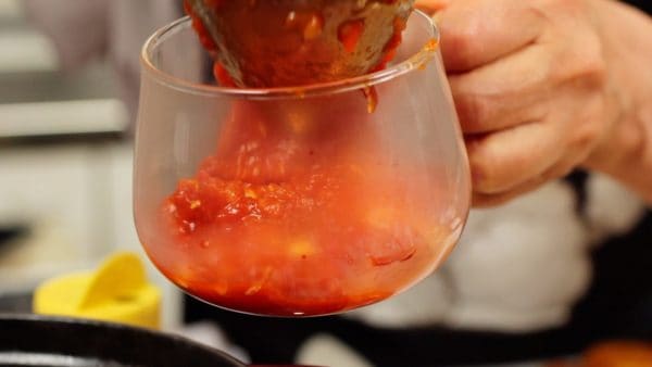 Ladle the hot tomato dipping sauce into a bowl.