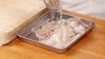Coloca las piezas de calamar en una bandeja y añade sake. Luego agítalos para cubrirlos uniformente.